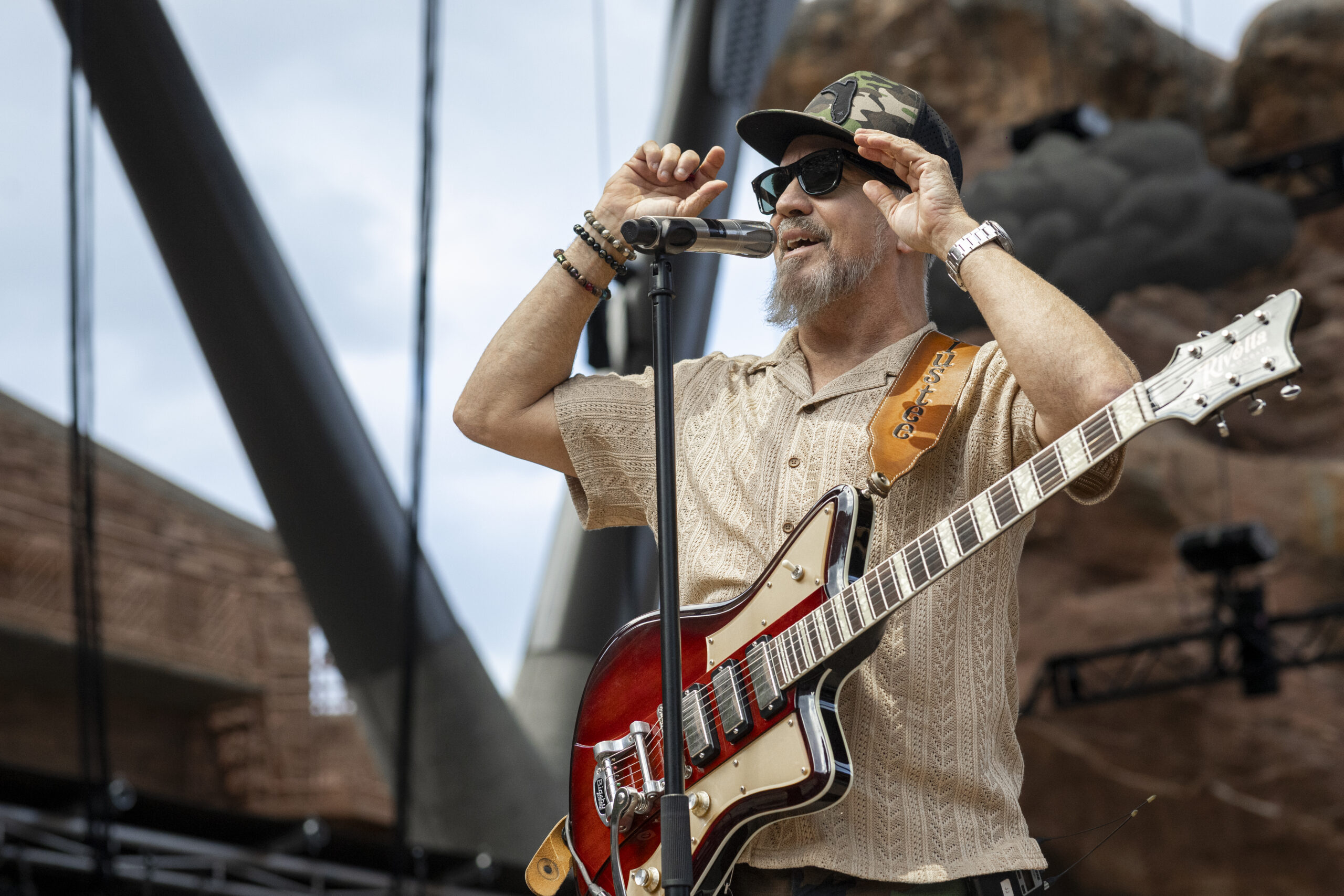 Guitarist adjusts his sunglasses while performing at Red Rocks.