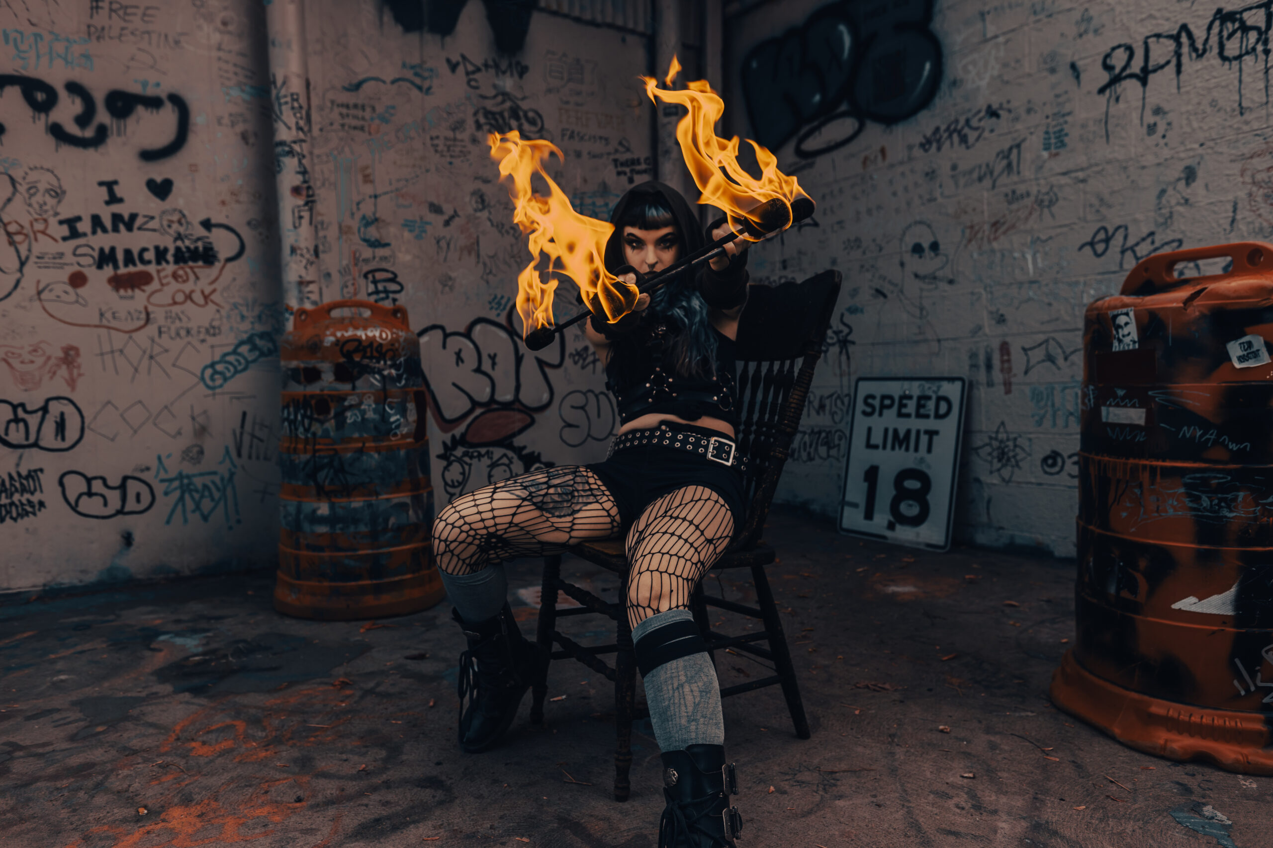 Fire performer aims two flaming batons toward the camera.