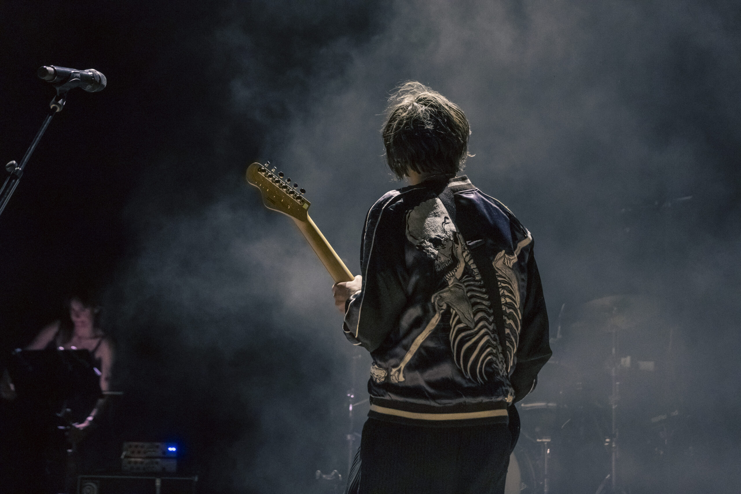 Bright Eyes guitarist faces away beneath stage smoke at Red Rocks.