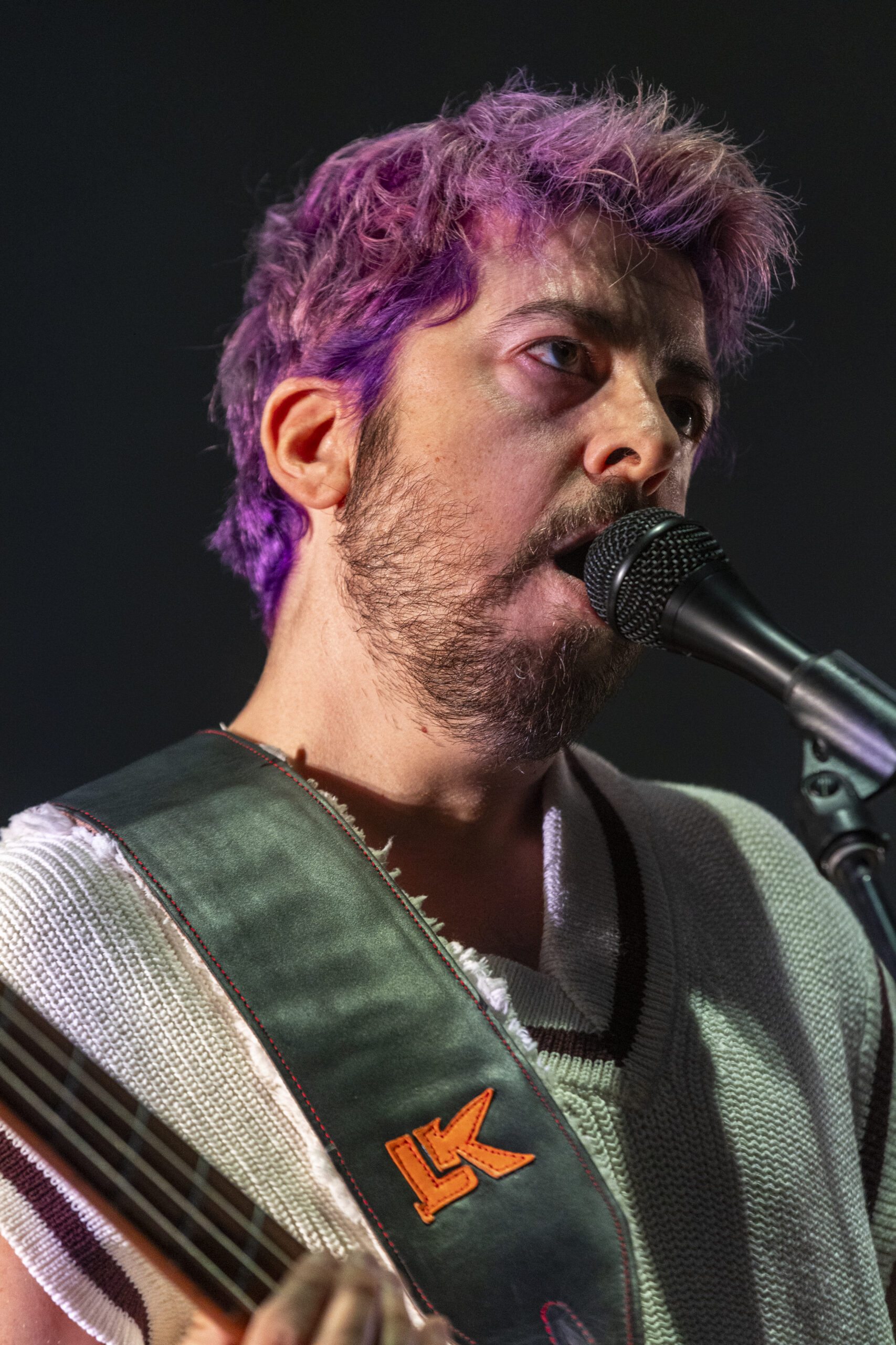 Bright Eyes vocalist sings under purple stage light at Red Rocks.