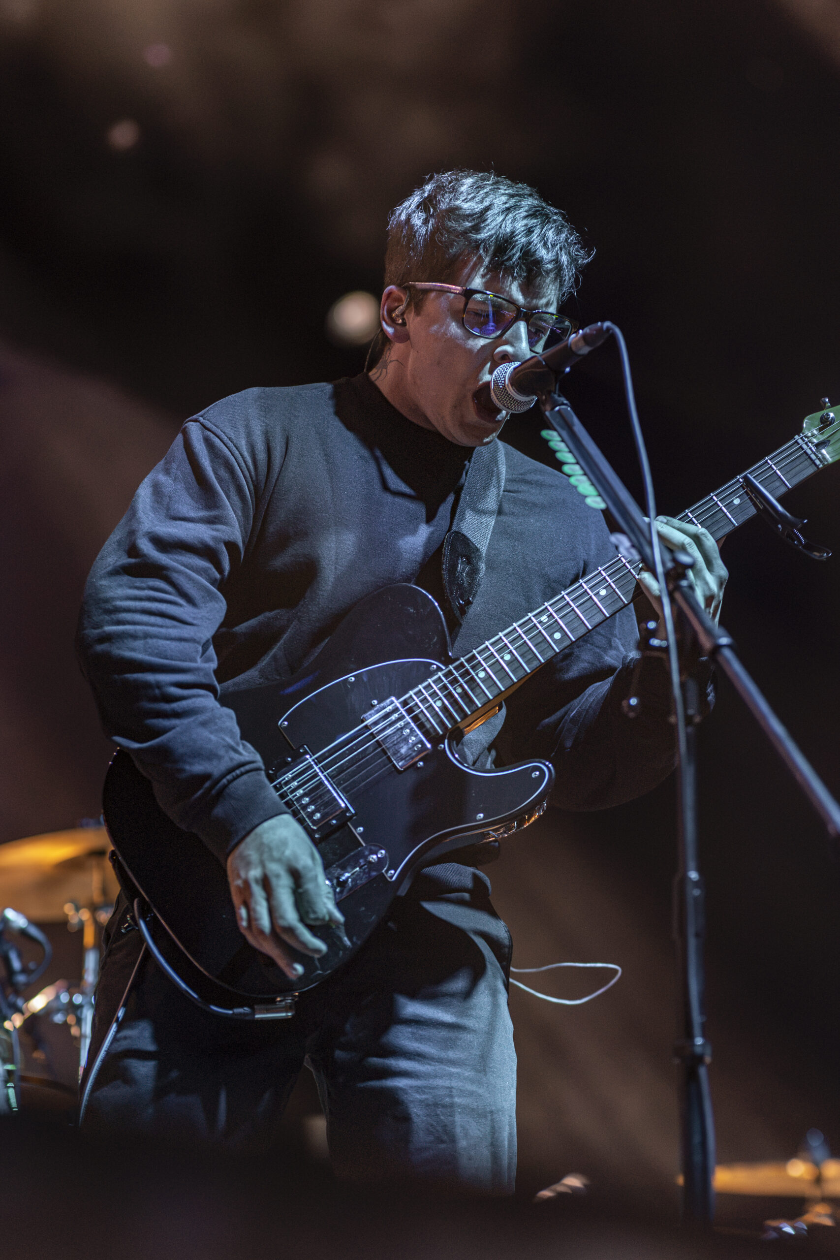 Chiodos guitarist sings while playing under blue and amber light.