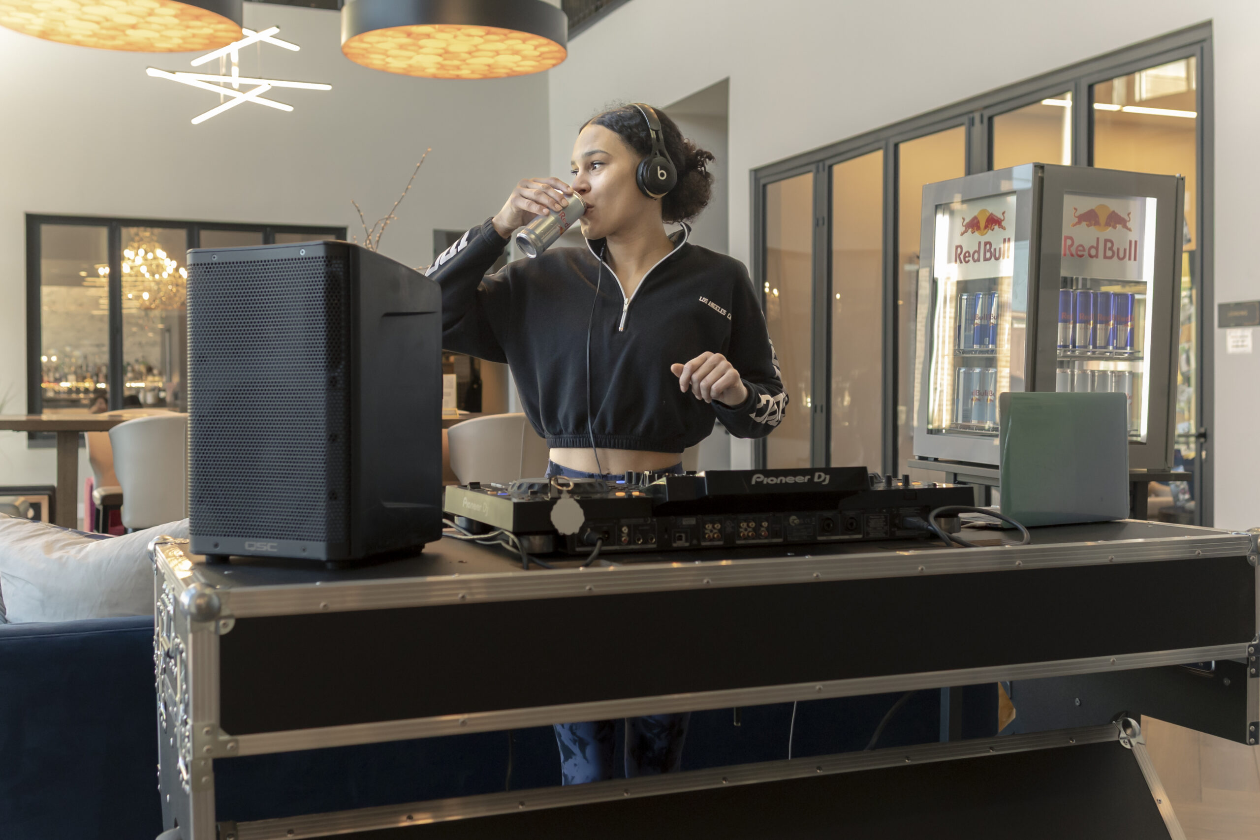 DJ drinks Red Bull beside a branded cooler during an event at The River Yoga.