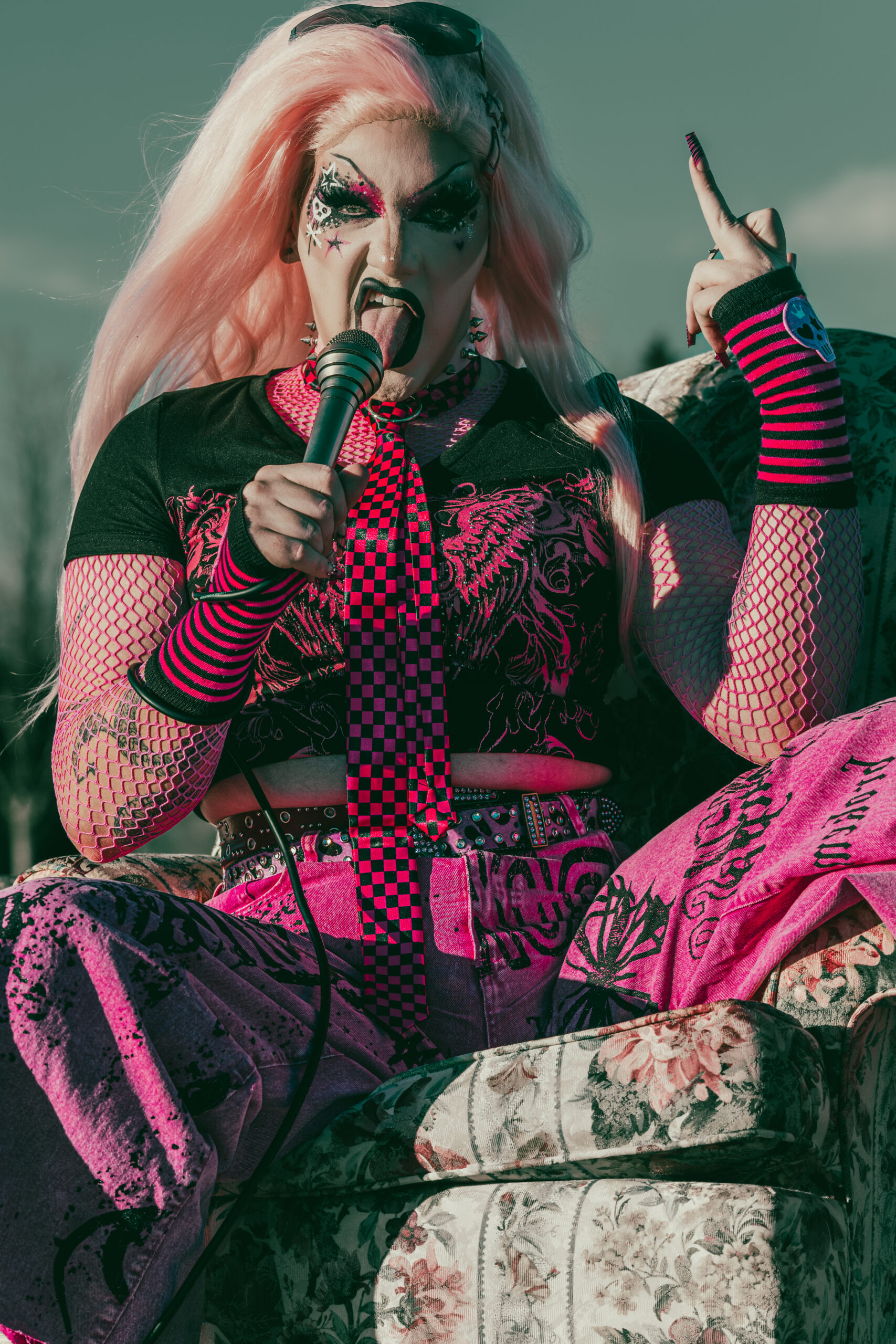 Minerva performs into a microphone in a vivid pink-and-black look.